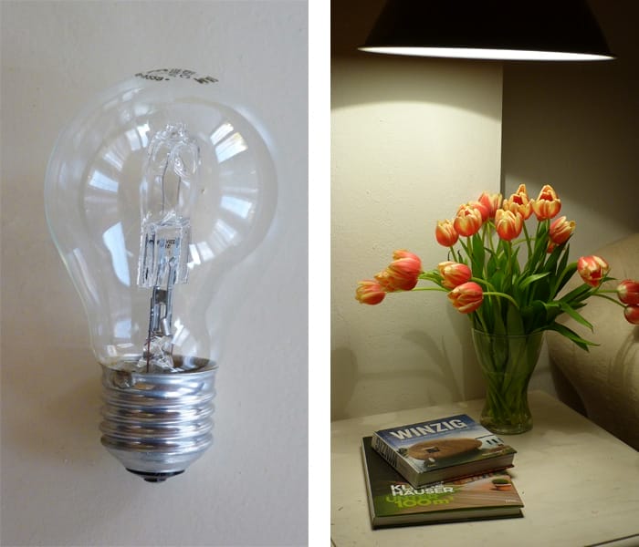 Eine Energiesparlampe vor hellem Hintergrund und ein Tulpenstrauß auf Nachttisch unter Lampe und zwei Magazinen unter Deckenl