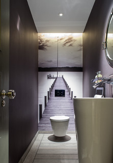 Schmales, langes WC mit flacher, runder Toilette und Waschbecken. Fototapete mit Holzsteg-Motiv (Foto: Vastu Interior Design