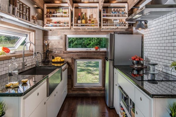 Eine moderne Tiny House Küche mit Spüle, Kochfeld, Kühlschrank und cleveren Stauraumlösungen