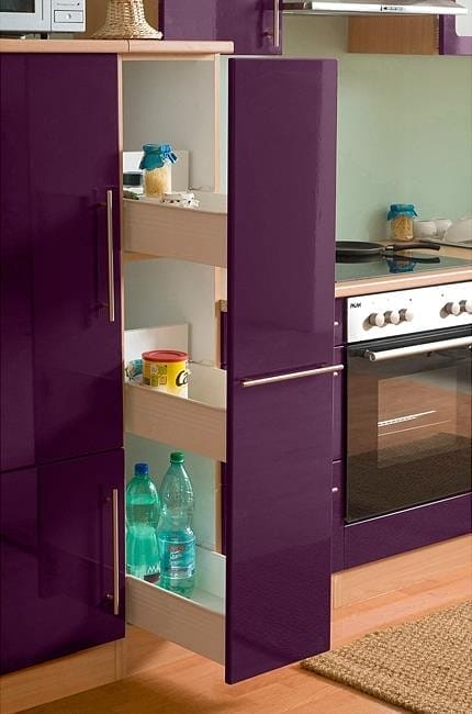 Offener Hochschrank mit Auszügen für Lebensmittel in violetter Küche mit Backofen, daneben Backofen und Kochfeld