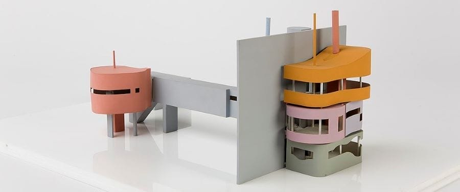 Architekturmodell mit runden und eckigen Baukörpern in Rosa, Orange, Grau und Hellgrün, auf weißem Grund