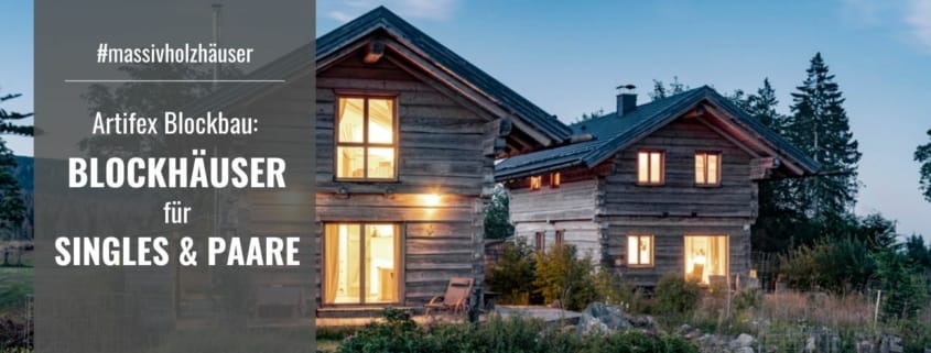 Zwei Blockhäuser von Artifex Blockbau im Abendlicht, die Fenster leuchten warm von innen hell