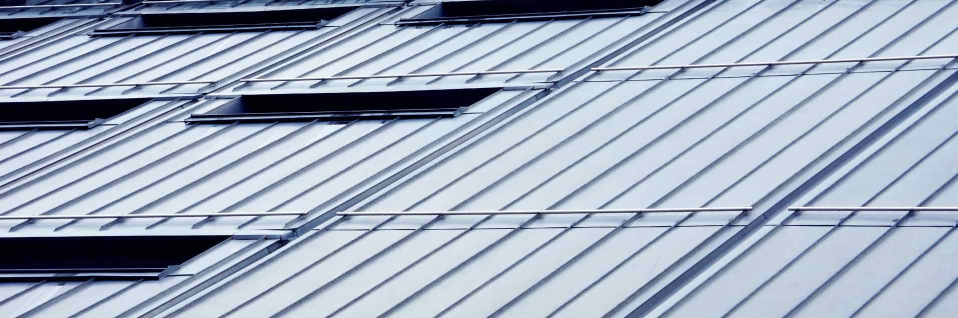 Metallgedecktes Dach mit mehreren Dachfenstern und horizontalen Schneestoppstoppernstoppernutzgittern