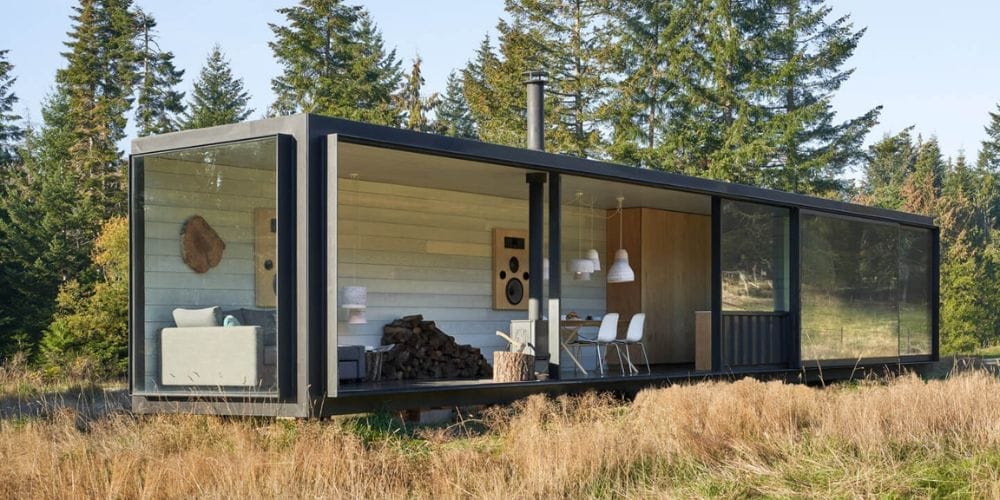 Ein modernes Wohnhaus aus einem umgebauten Seecontainer inmitten einer grünen Landschaft mit Bäumen