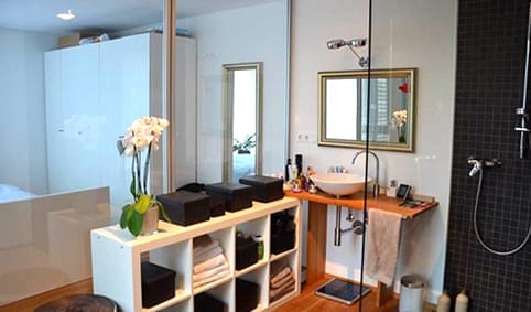 Modernes Badezimmer mit runder Aufsatzwaschschale, Holzwaschtisch und dunklen Fliesen in der Duschkabine