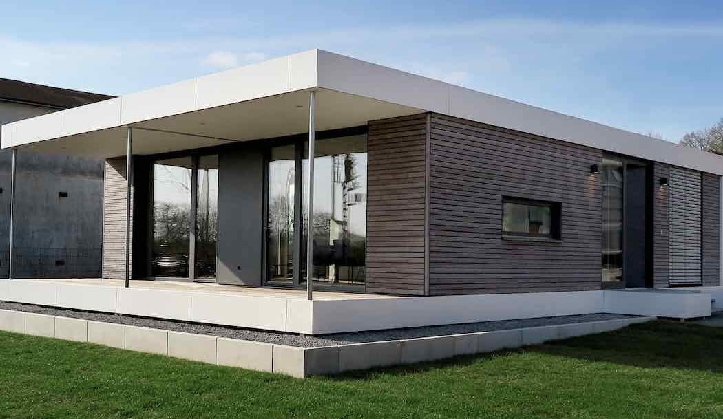 Modernes Minihaus mit schlichter Holzfassade und großer überdachter Terrasse aus hellem Material