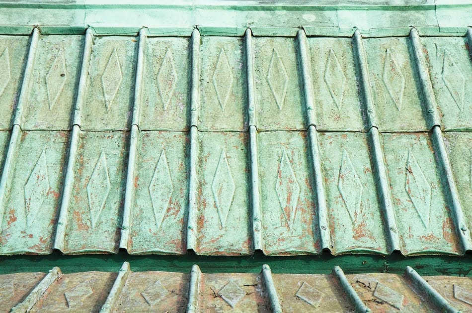 Nahaufnahme eines verwitterten Metalldachs mit Rautenmusterartigen Rauten und grünspanähnlichen Verfärbungen