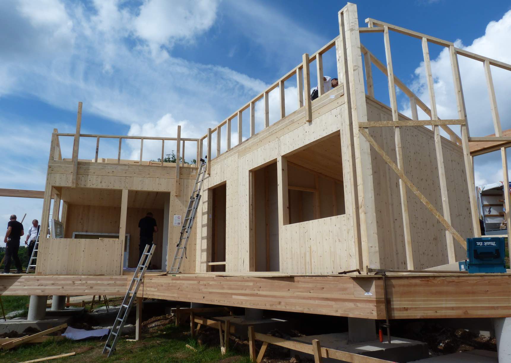 Rohbau eines Minihauses aus Holz mit sichtbaren Holzbalken und Fensteröffnungen unter blauem Himmel