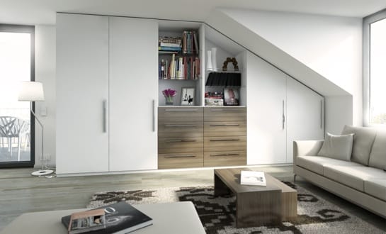 Wohnzimmer mit Dachschräge, weißem Einbauschrank, Kommode, beigem Sofa und Couchtisch und Teppich mit Ethno-Muster