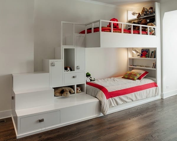 Weißes Hochbett mit Treppe, integrierten Fächern und Staukästen, daneben ein rotes Kinderbett