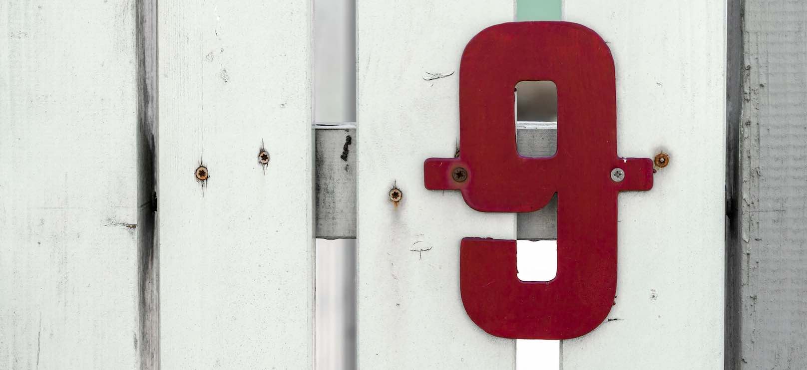 Rote Hausnummer 9 an einer hellen Hauswand