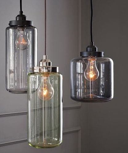 Drei Hängelampen im Industrie-Look mit gläsernen Zylindern in Grau und Grün sowie Edison-Glühbirnen
