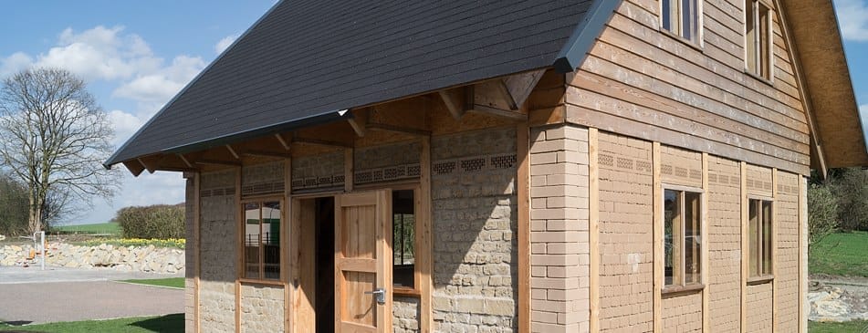 Neues Holzhaus mit dunklem Dach und Naturstein- sowie Holzfassade
