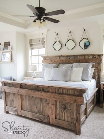Rustikales Holzbett mit grauer Bettwäsche und weißen Kissen im Schlafzimmer – Quelle: Shanty 2 Chic