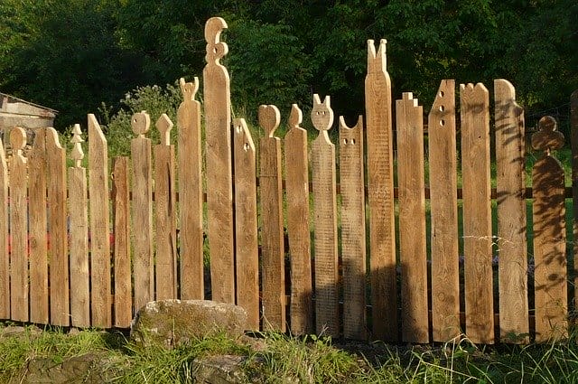 Ein Holzzaun mit einzelnen Holzlatten in Form von Comic-Figuren als Sichtschutz