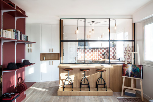Offener Wohnbereich mit rotem Regal, Küche durch schwarzes Industriefenster abgetrennt (Foto: Bän Architecture)