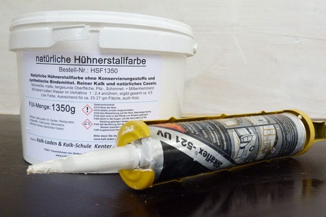 Eimer mit natürlicher Hühnerstallfarbe und eine Kartusche Sikaflex-521 UV Dichtstoff