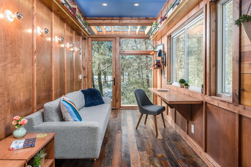 Innenansicht eines Tiny Houses der Tumbleweed Tiny House Company mit Sofa und Fensterfront, Schreibtisch und Fensterfront