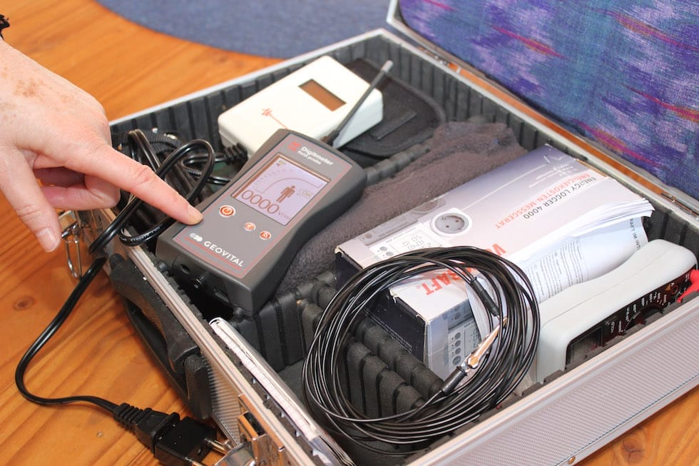 Eine Hand tippt auf ein Elektrosmog-Messgerät von Geovital, das in einem Messkoffer liegt