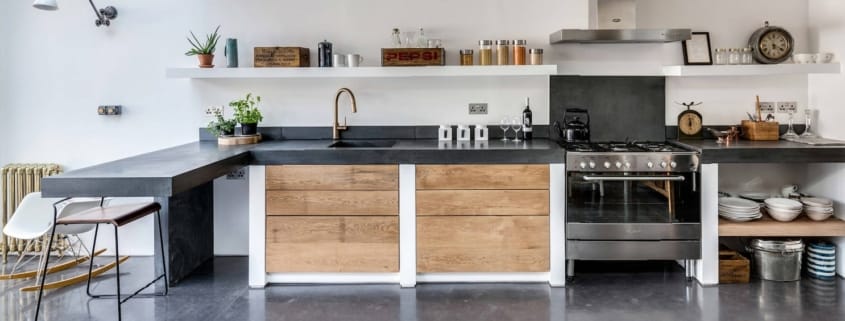 Offene Küche mit poliertem Betonboden und Arbeitsplatte, Holzschränken und Gasherd (Photo: Paper House Project – Mehr Bilder