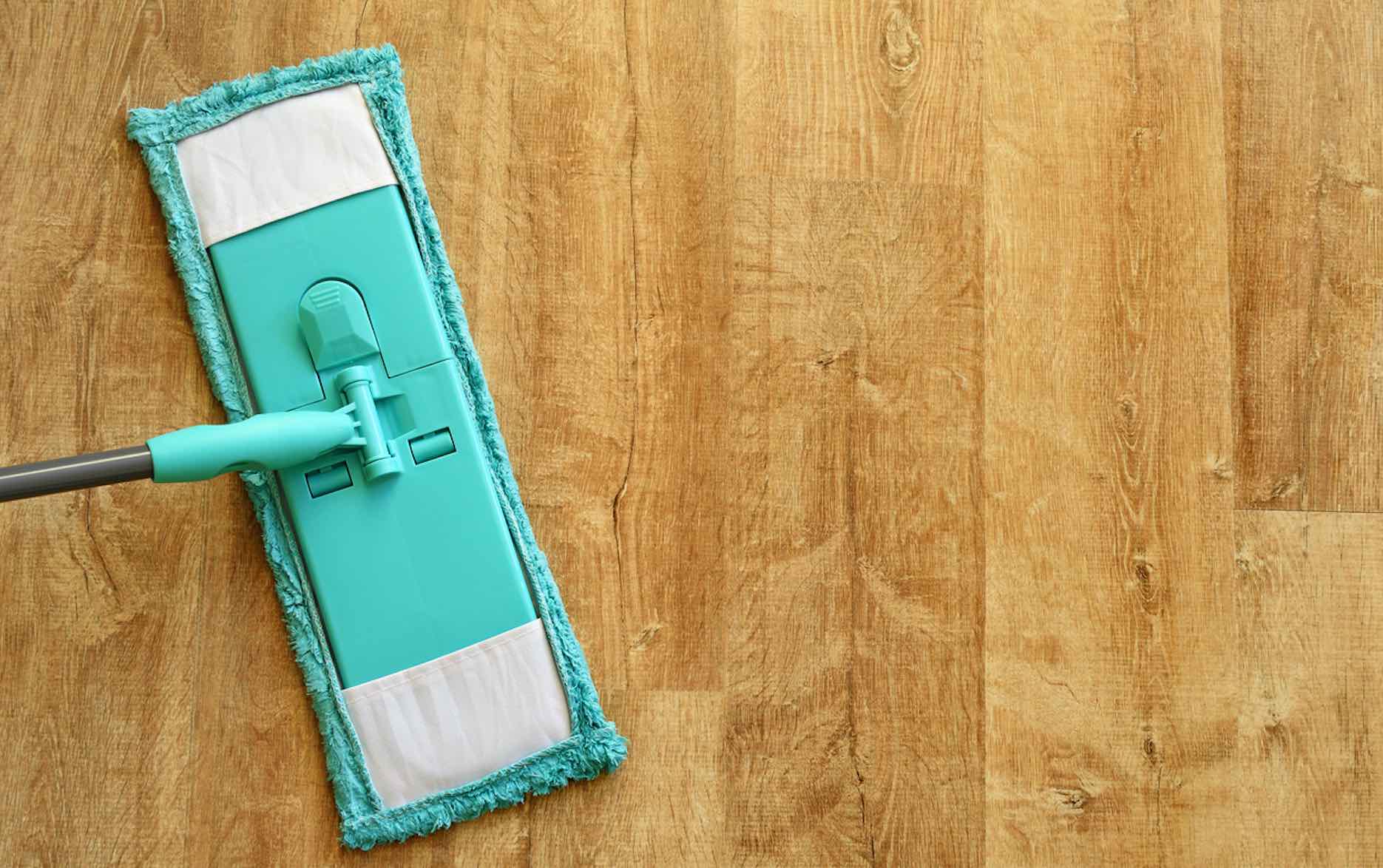 Türkisfarbener Wischmopp auf einem braunen Laminatboden mit Holzmaserung