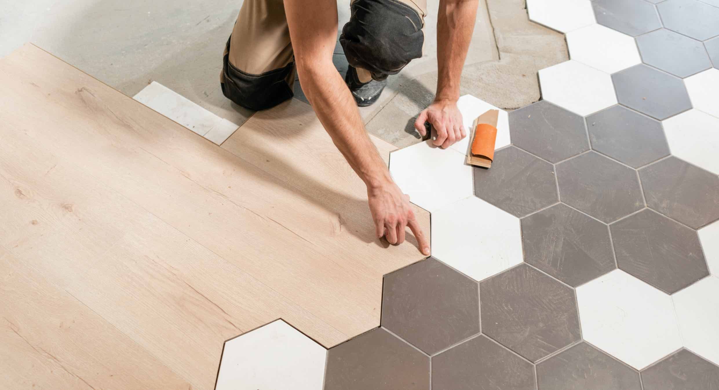 Verlegung von hellem Laminat und sechseckigen Fliesen in Grau und Weiß auf einem Fußbodenheiz-Elementen in dunklem Grau und W