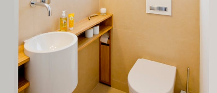 Modernes, kleines Badezimmer mit ovalem Waschbecken, Holzelementen und cremefarbenen Fliesen