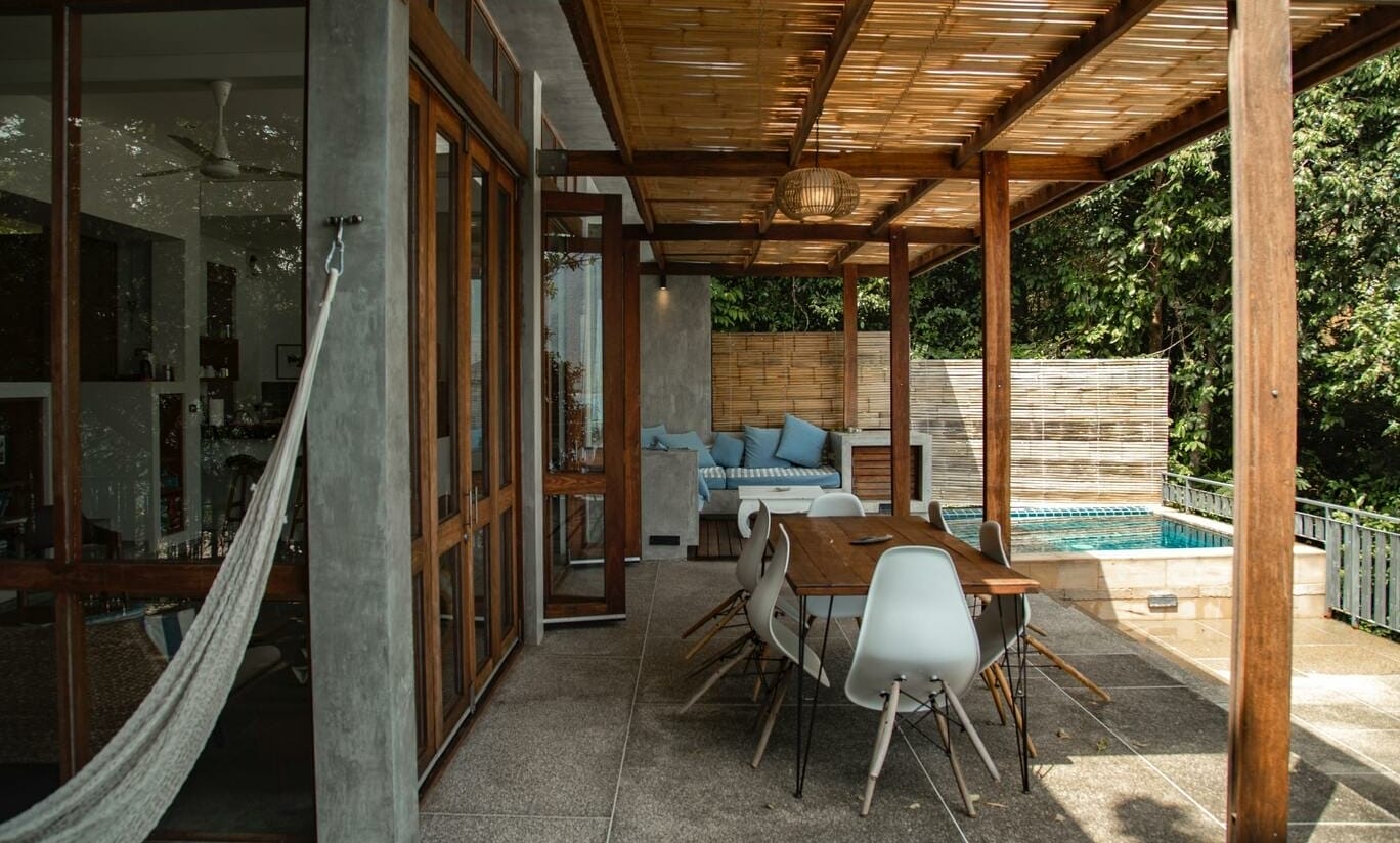 Eine große Terrasse mit Esstisch, Sofa und Hängematte. Im Hintergrund ist ein kleiner Pool zu sehen