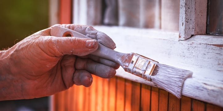 Nahaufnahme: Hand streicht Fensterrahmen mit weißer Farbe