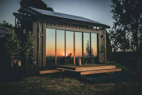 Modernes Haus aus Seecontainern mit Solarmodulen auf dem Dach, im Sonnenuntergang. (Foto: Larnook.co)