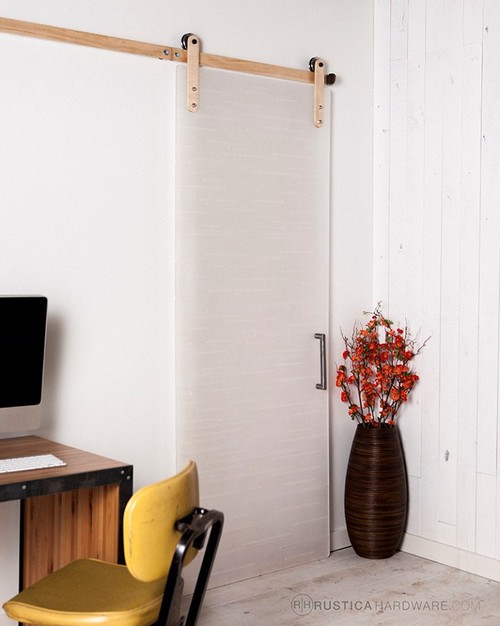 Weiße Schiebetür mit Holzschienen und schwarzem Griff in einem modernen Arbeitszimmer mit Schreibtisch