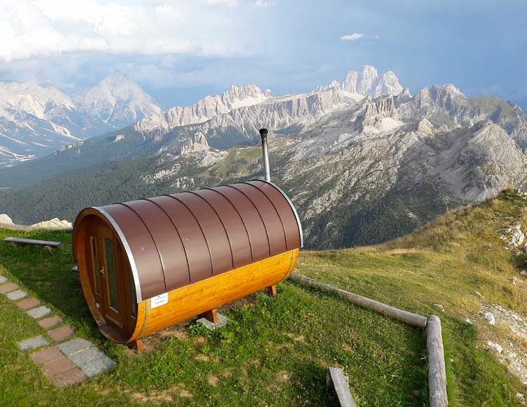Fasssauna in den Bergen mit Blick auf weitläufiges Tal und bewaldete Gipfel