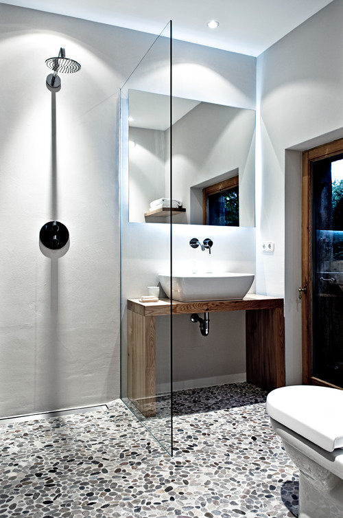 Modernes Badezimmer mit Kieselsteinboden, begehbarer Dusche und Holztisch mit Aufsatzwaschbecken