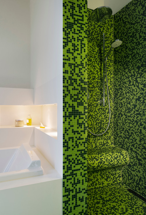 Bodengleiche Dusche mit Duschsitz und grünen Mosaikfließen; links eine Badewanne mit Ablage