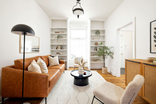 Wohnzimmer mit braunem Ledersofa, hellem Teppich, weißen Regalen und beiger Chaiselongue