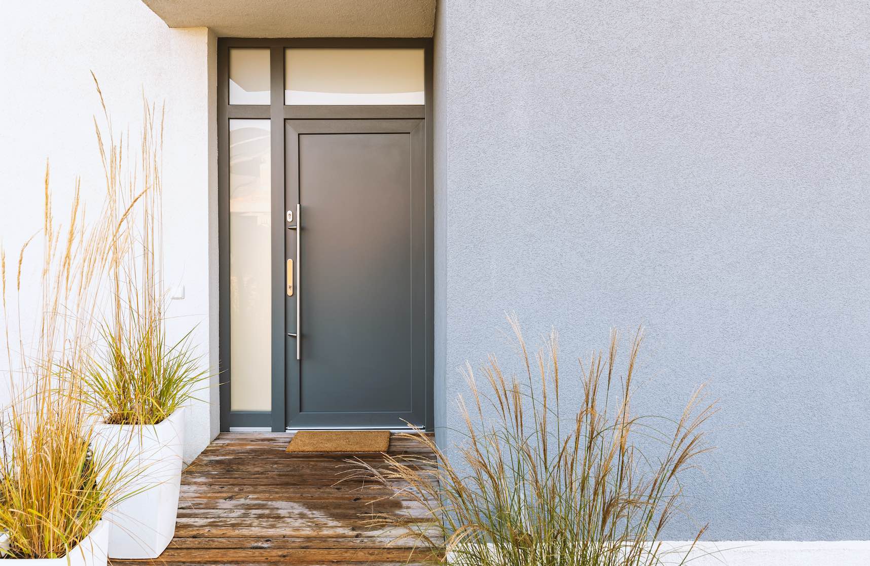 Moderne graue Haustür aus Aluminium oder Stahl mit Glaseinsätzen und hölzernem Vorbau