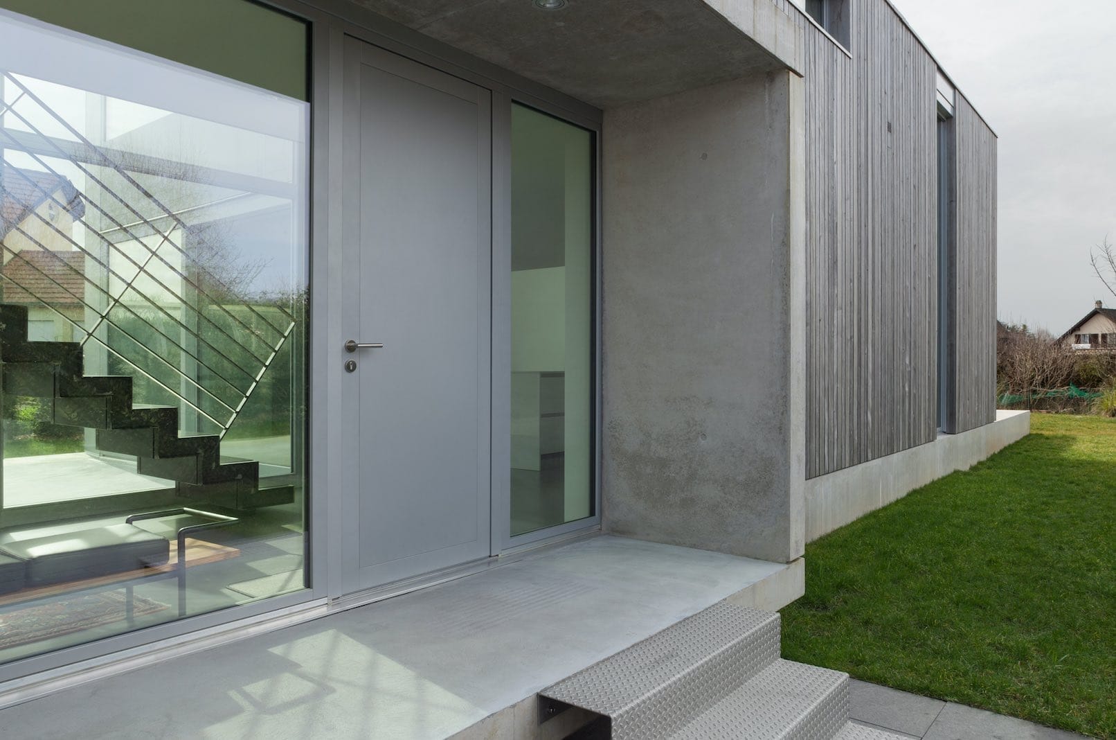 Eine moderne Haustür aus grauem Aluminium mit Sichtfenstern im Eingangsbereich eines Minihauses