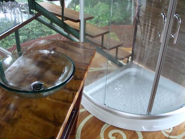 Blick auf ein Badezimmer mit einer Glaswaschschale auf einer Holztheke und einer Duschkabine aus Glas