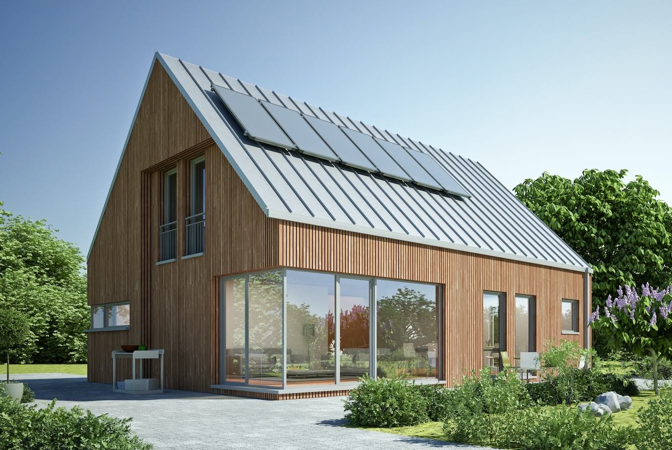 Holzhaus mit Solaranlage auf dem Dach und großen Glasfronten, umgeben von einem grüner Natur