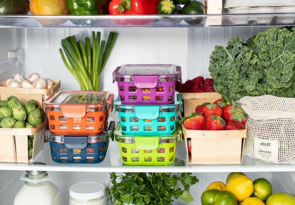 Offener Kühlschrank mit frischem Gemüse und Obst in Holzkisten, sowie bunten Vorratsdosen