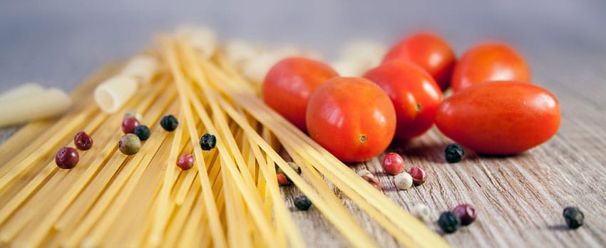 Spaghetti, Cherrytomaten und Pfefferkörner auf einem Holztisch