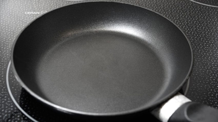 Eine schwarze Pfanne steht auf einem CERAN-Kochfeld mit einzelnen Kochzonen