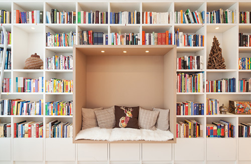 Großes Bücherregal mit integrierter Leseecke, kuscheligen Kissen und Kunstwerkeltem Hirschmotiv