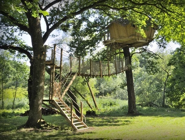 Baumhaus im Val de Bonnal, erreichbar über Holztreppe und Hängebrücke, umgeben von grünen Blättern