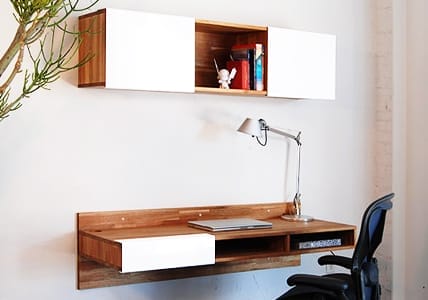 Moderner Arbeitsplatz mit Laptop auf Holzschreibtisch, dazu passendes Wandregal, Drehstuhl und Schreibtischlampe