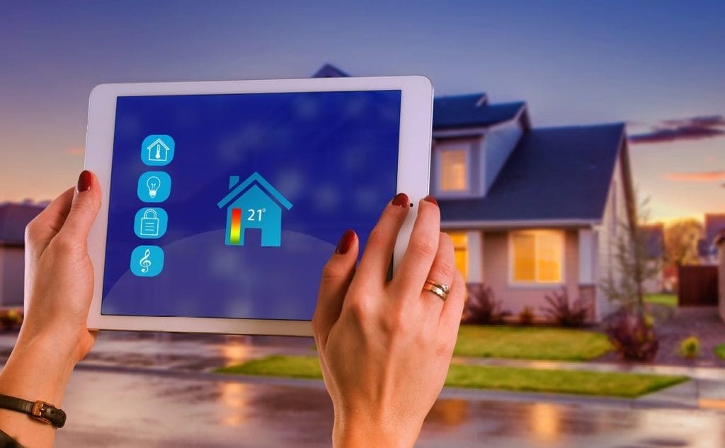 Hände mit Tablet steuern ein Smart Home, die Temperaturanzeige liegt bei 21°C. 21°