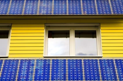 Blau-schwarze Solarmodule bedecken die gelbe Fassade und das Dach eines Hauses