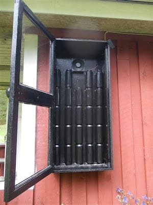 Offener DIY Warmluft-Kollektor mit schwarzen Dosen auf rotem Untergrund