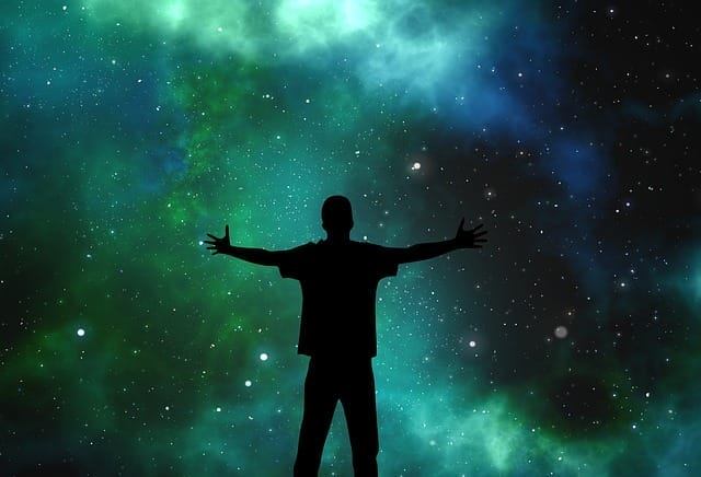 Abbildung eines Sternenhimmels in Grün- und Blautönen mit einer Person in Silhouette, die die Arme ausbreitet