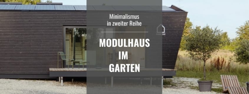 Modernes, dunkelbraunes Modulhaus mit Solaranlage auf dem Dach und großer Fensterfront, umringt von Natur